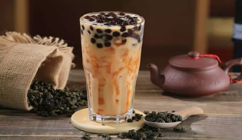 Ly trà sữa có trân châu bên cạnh ấm trà
